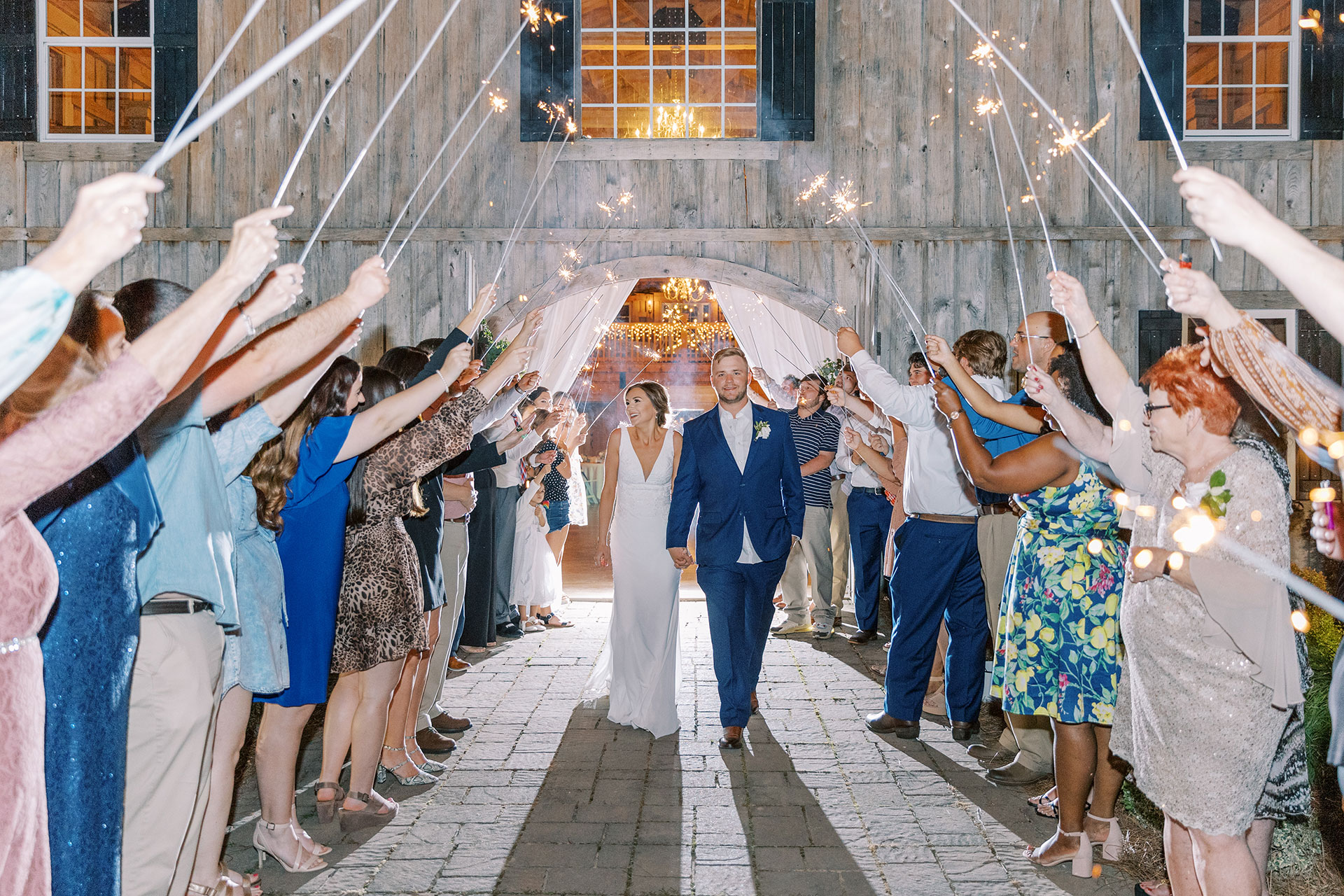 smiling married couple walking out of reception with sparklers