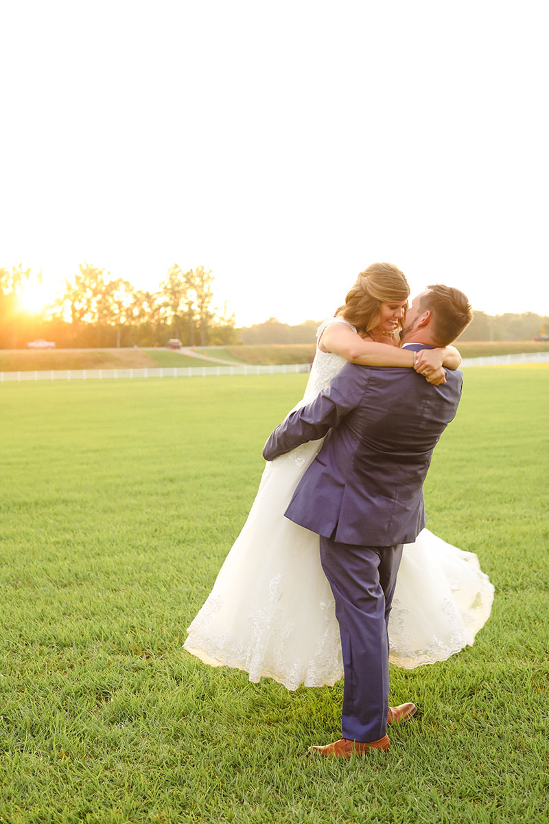 married couple embracing in a field at sunset