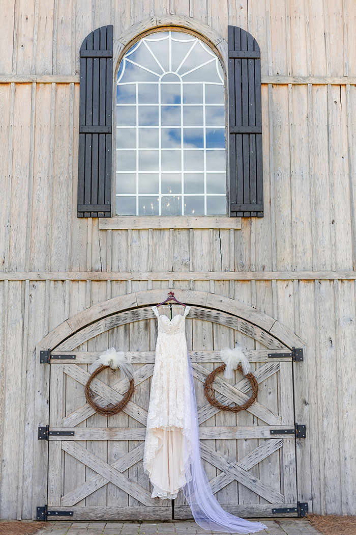 wedding dress hanging on front of barn doors